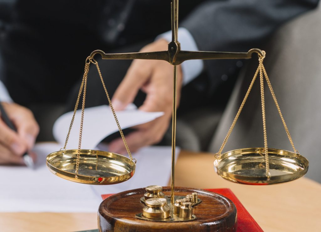 golden-justice-scale-book-stack-front-lawyer-signing-document